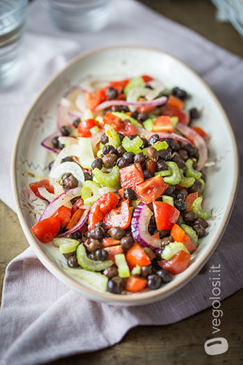 Insalata di ceci neri, sedano, pomodori e cipolle con olio alle erbe