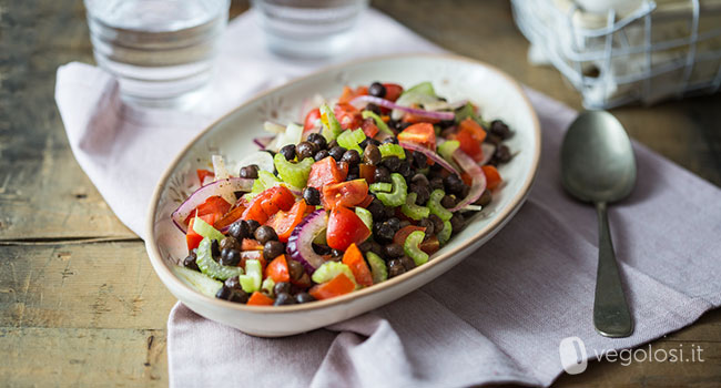 Insalata di ceci neri, sedano, pomodori e cipolle con olio alle erbe