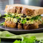 Sandwich ripieno di crema di ceci e avocado con olive e rucola