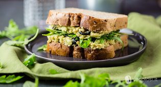 Sandwich ripieno di crema di ceci e avocado con olive e rucola