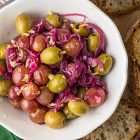 Aperitivo di olive, uva al forno, cipolle caramellate e limone